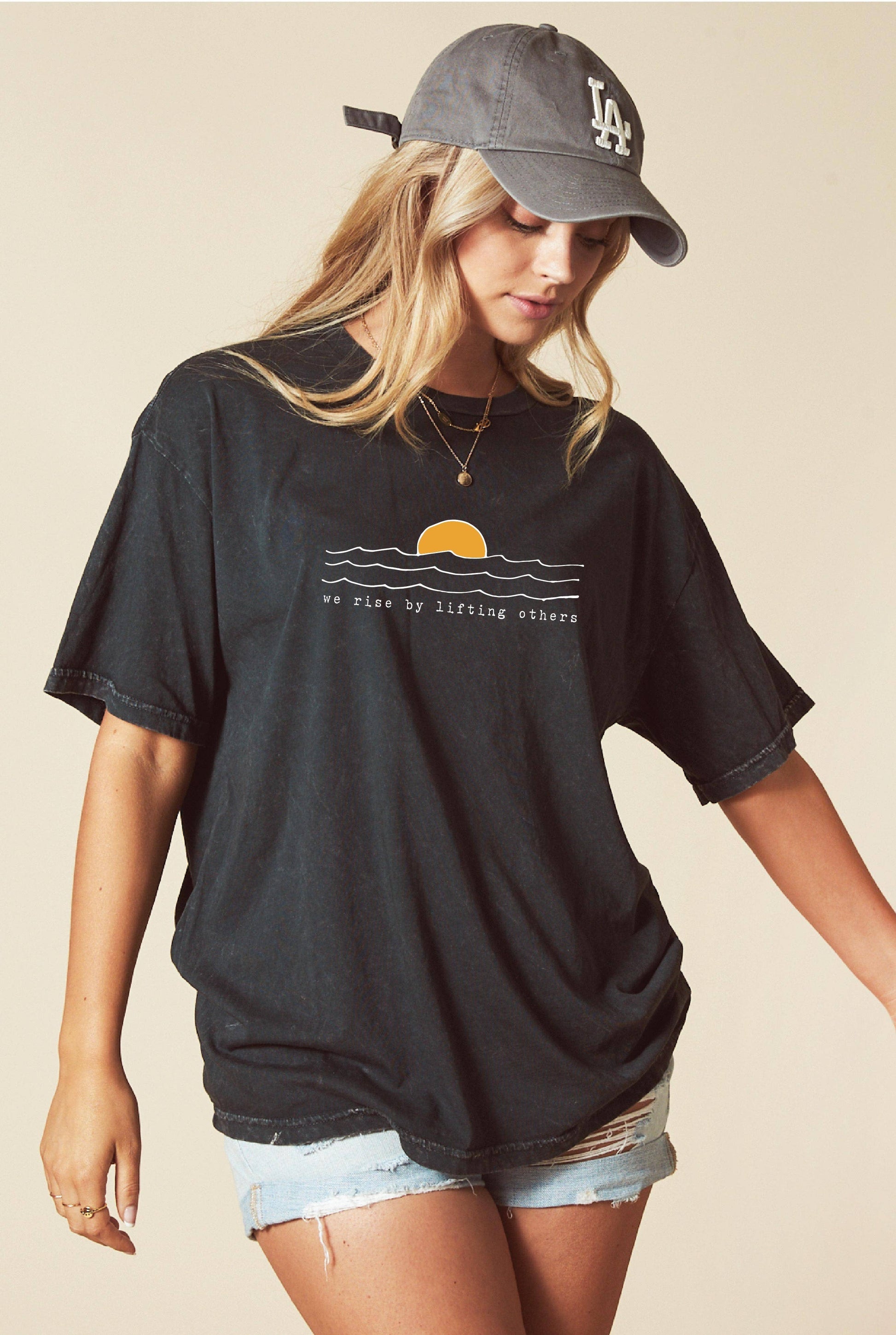 Woman wearing a black t-shirt with a graphic design and a cap on a beige background